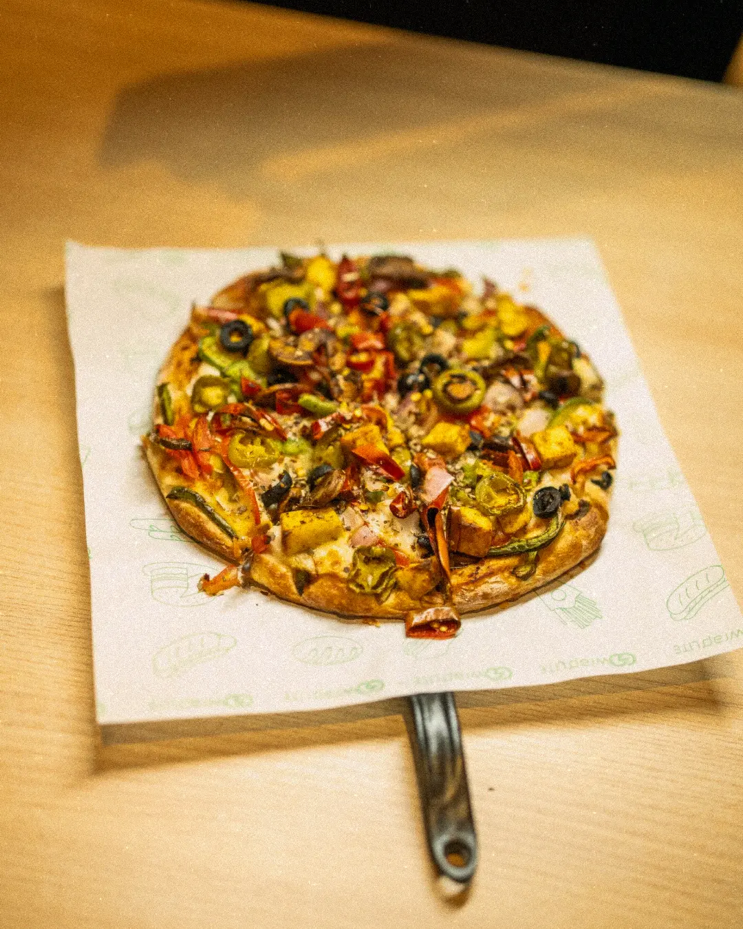 Veggie loaded pizza on a wooden table at Shivansh Food Park Dhamtari