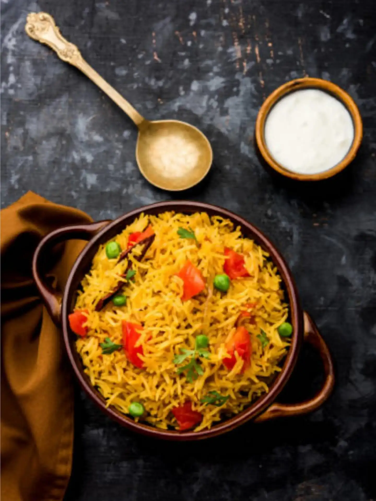 Aromatic veg pulao with peas and tomato plated on dark stone at Shivansh Food Park